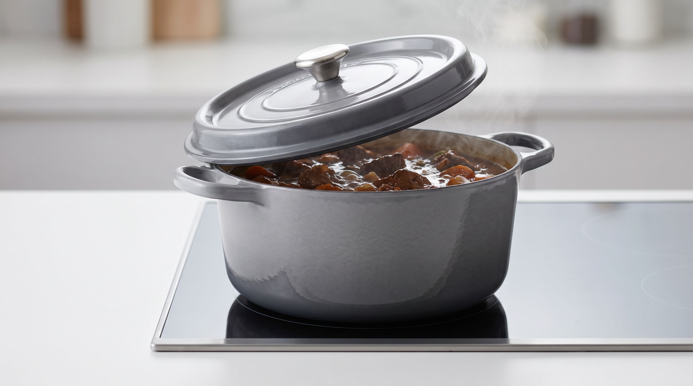 Enameled cast iron Dutch oven with the lid tilted open on a stovetop, showing a browned beef braise inside